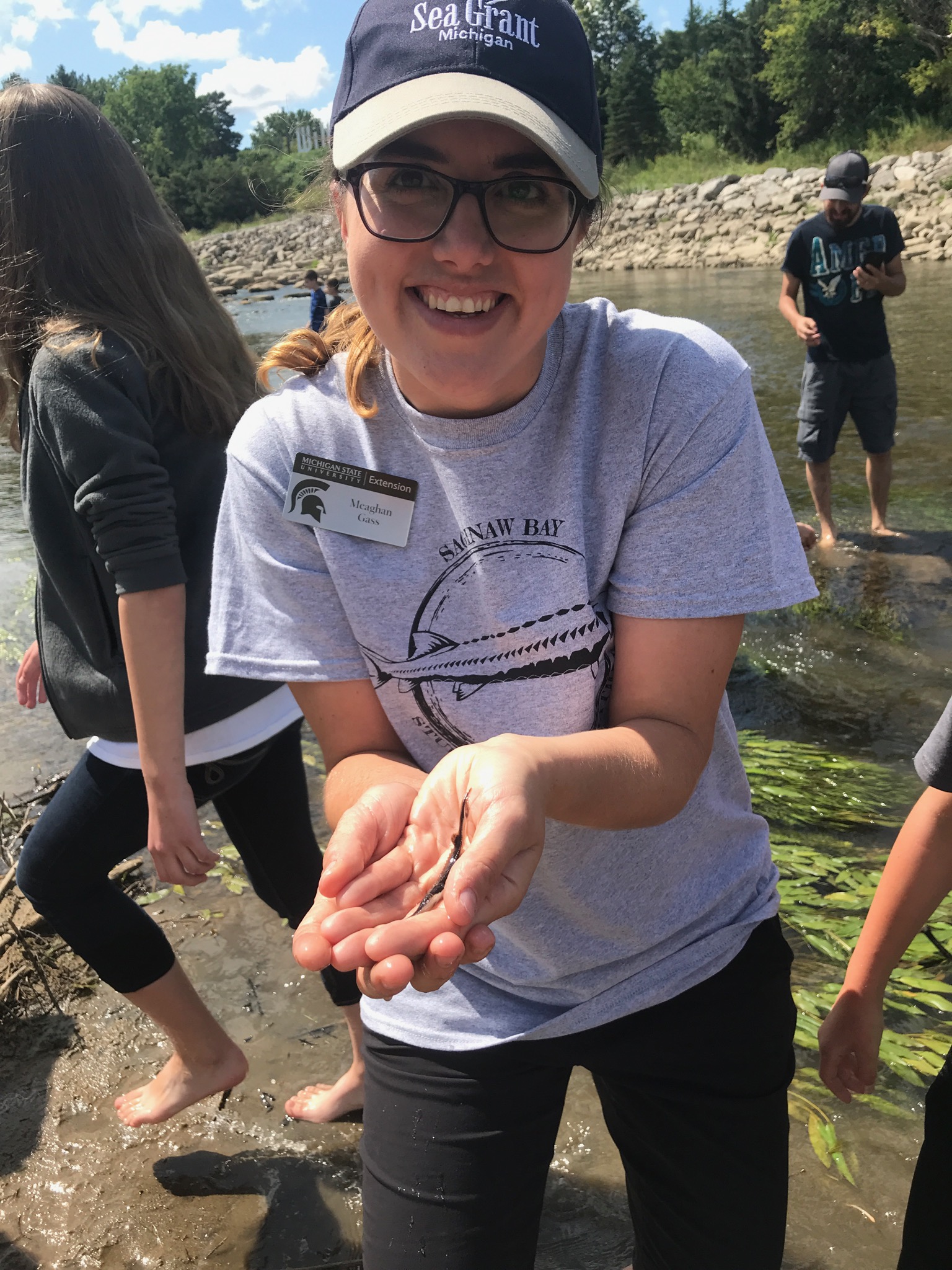 Meaghan Gass holds a juvenile sturgeon cupped in her hands.